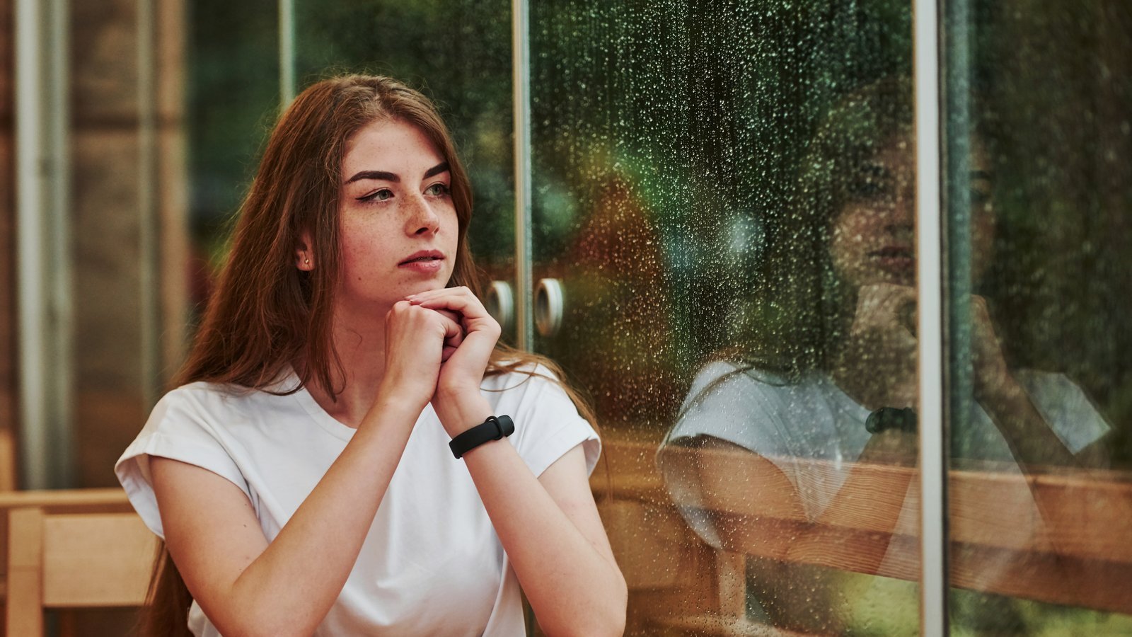 A woman sitting quietly by a window in soft light