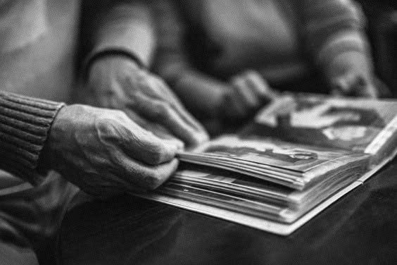 Older hands turning the pages of a photo album, in black and white