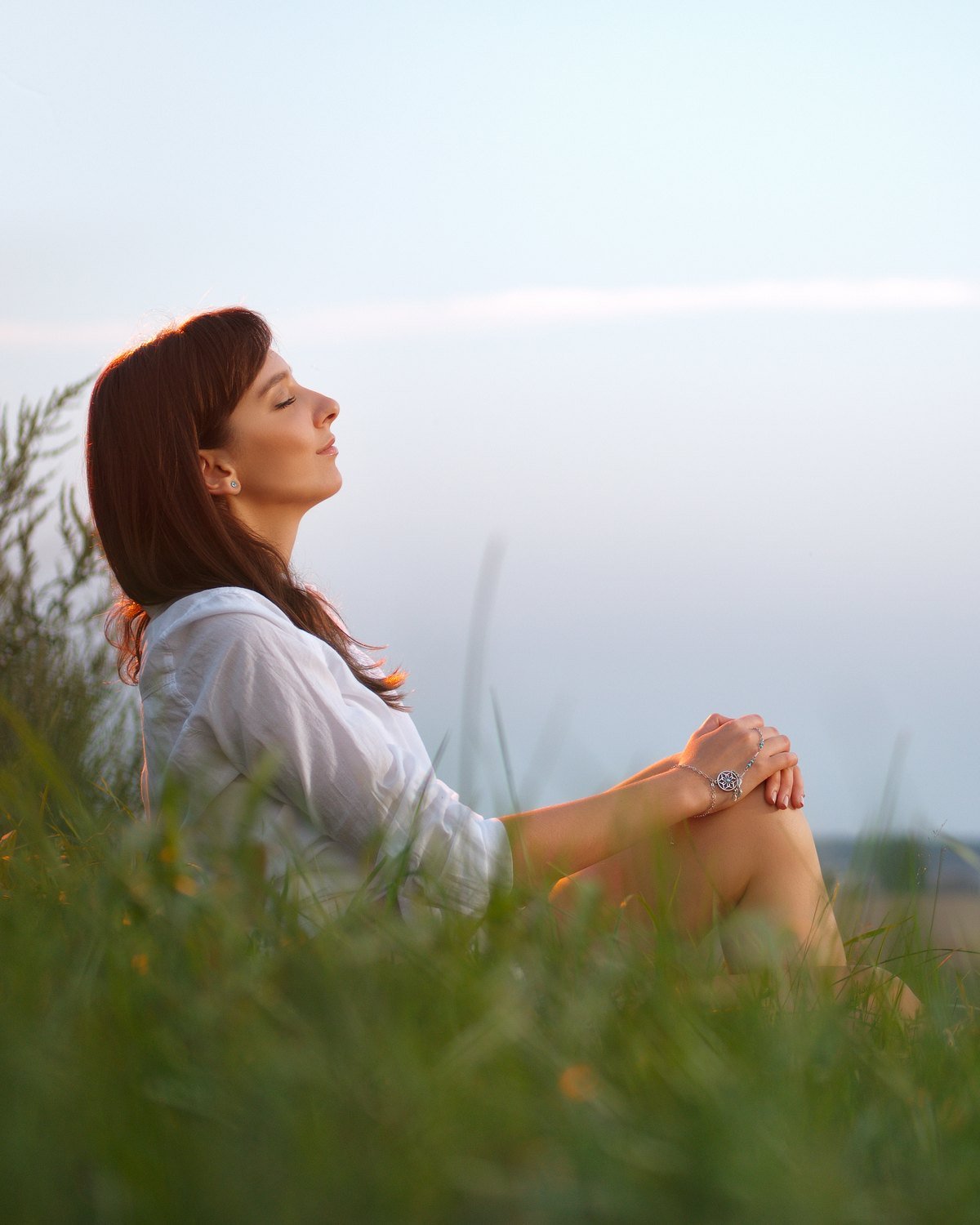 A person sitting peacefully in a meadow at dusk